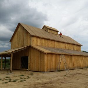 14x30 Dairy Barn Plans 17 Gable barn with wraparound porch and unstained natural pine exterior under a clear blue sky